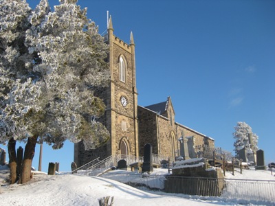 Magheragall Parish Church stands out against the snow and the blue sky. 